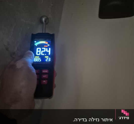 מד לחות על קיר עם יד אוחזת בו